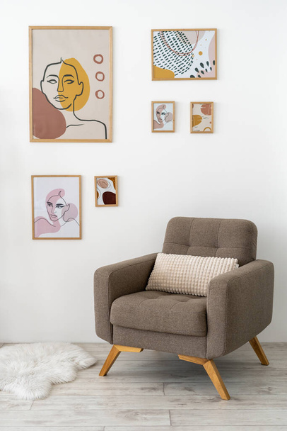 Вертикальное фото современной гостиной в современном доме с произведениями искусства в рамке на кирпичной стене, мягкой мебелью, удобным креслом и мехом на полу
 - Фото, изображение