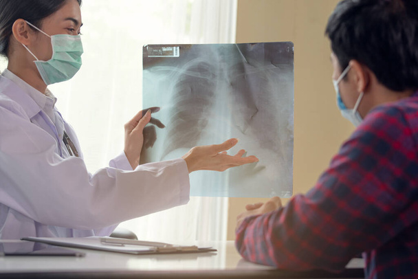 Jonge Aziatische vrouwelijke arts uitleggen long x-ray aan patiënt, gezondheidszorg en medische concept - Foto, afbeelding