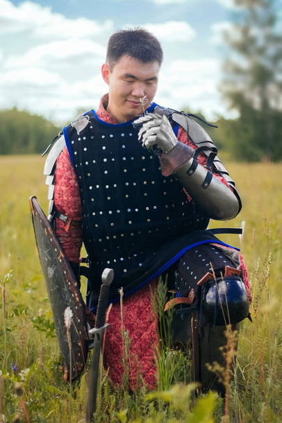 A medieval Asian warrior sits in a field in tall grass. - Fotó, kép