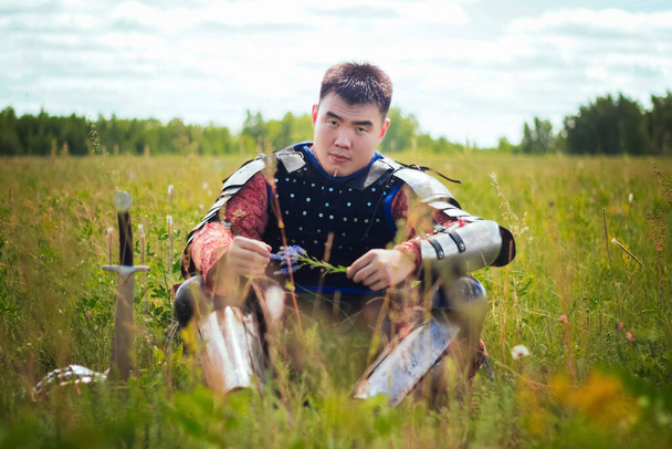 A medieval Asian warrior sits in a field in tall grass. - Fotó, kép