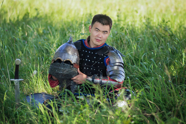 A medieval Asian warrior sits in a field in tall grass. - Foto, Imagen