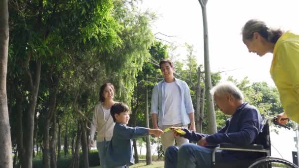 Три поколения азиатской семьи наслаждаются активностью на открытом воздухе в парке
 - Кадры, видео