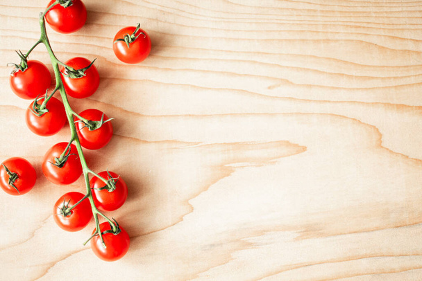Red cherry tomatoes on a branch on a wooden Board. Left an empty space on the right - Fotoğraf, Görsel