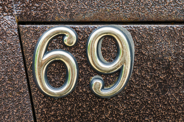 кількість будинку становить шістдесят дев'ять на залізному коричневому тлі. 69-річний
. - Фото, зображення