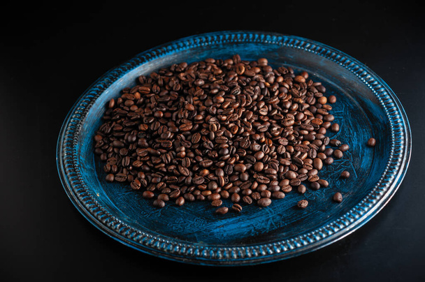 καβουρδισμένοι αρωματικοί κόκκοι καφέ κοντά πασπαλισμένοι σε τραπέζι - Φωτογραφία, εικόνα