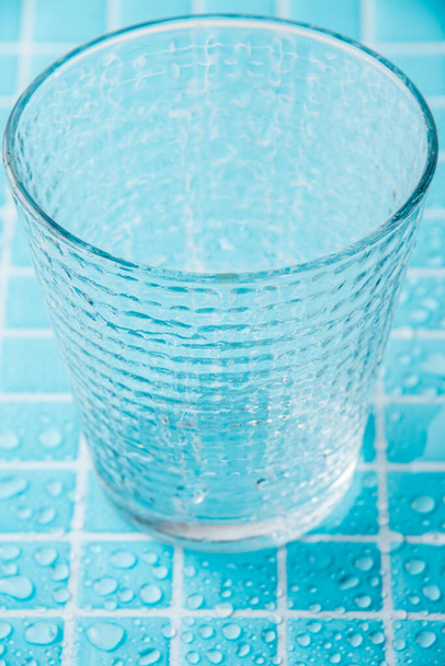 Islak cam bir taklacı, ıslak açık mavi mozaik üzerine seçici bir odak ile havadan görünüm, dikey - Fotoğraf, Görsel