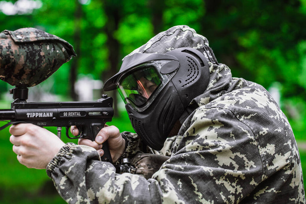 Closeup Portrait of Paintball Player In Full Gear At The Shooting Range with Paintball marker in Protective Mask and Camouflage Pixels - Photo, Image