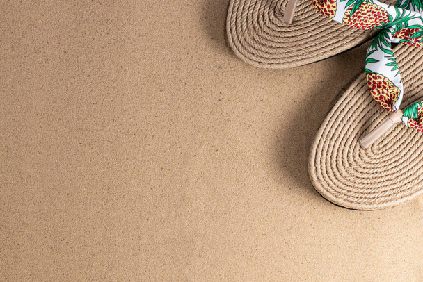 Summer vacation concept. Hat and flip flops on sand background with a copy of space. Summer background. - 写真・画像