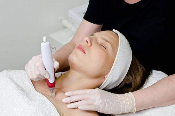 Mooie vrouw liegen en ontvangen ultrasone scrubben procedure van ultrasone reiniging van een deel van het lichaam in schoonheidssalon - Foto, afbeelding