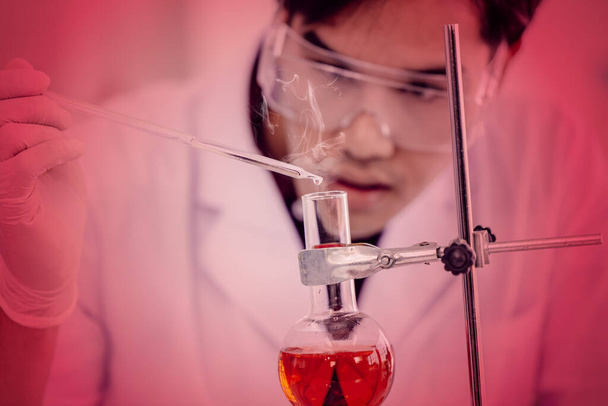 Fiatal ázsiai tudós tesztelés óvatosan a szörnyű veszély és a kockázat kémiai képlet vagy vírus a tudományos labor koncepció. - Fotó, kép
