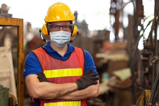 Worker wearing face shield or disposable face mask during working service in factory to prevent Coronavirus(Covid-19) or Air dust pollution in factory. - Photo, Image
