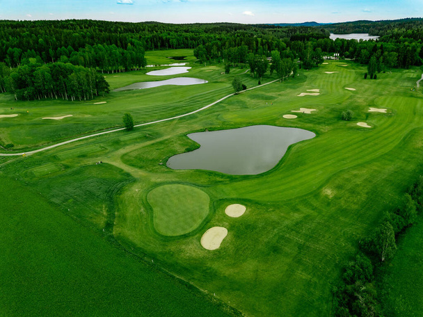 Widok z lotu ptaka na zielone trawy na polu golfowym ze stawami w Finlandii - Zdjęcie, obraz