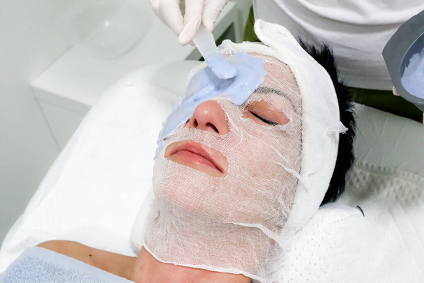 esteticista trabajador aplicando cosmética caviar despegar máscara para el cuidado de la piel facial a cliente femenino en salón de belleza
  - Foto, imagen