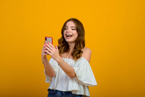 Excited woman with digital device. Studio shot of shocked girl holding smartphone. - Foto, afbeelding