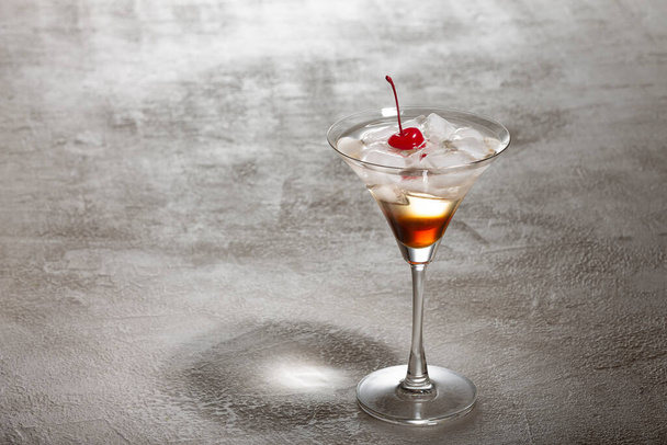 Κοντινό πλάνο ενός αλκοολούχου κοκτέιλ με ρούμι, πάγο και διακοσμημένο με κόκκινα κεράσια. Concept συνταγές και mixology. - Φωτογραφία, εικόνα