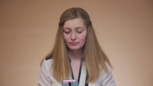 Młoda kobieta patrzy na smartfon - Materiał filmowy, wideo