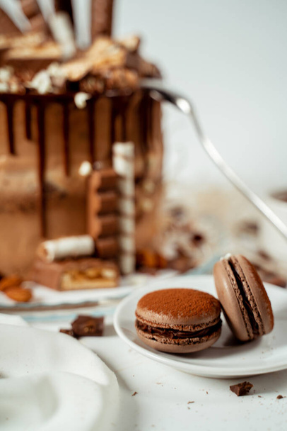 Chocolate cake decorated with various cookies and nuts on a glass plate and macaroons. Food photography. Advertising and commercial close up design - Foto, Imagem