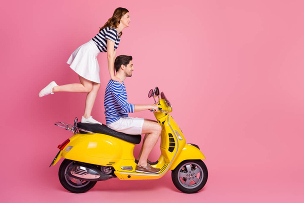 Profile side view portrait of his he her she nice attractive cheerful cheery funky carefree couple riding moped girl standing fooling having fun weekend isolated on pink pastel color background - Fotografie, Obrázek