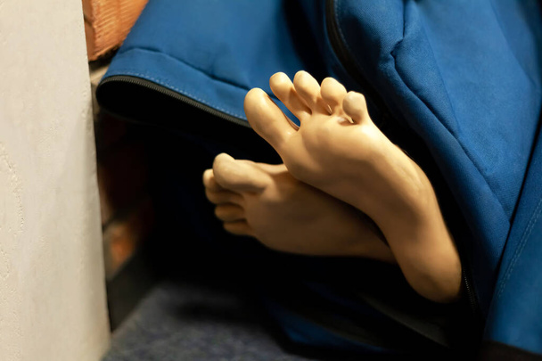 Dos pies de maniquí de entrenamiento de RCP, piernas sobresaliendo de una bolsa parecida a un cadáver, cadáver en una bolsa de cadáveres, primer plano, disparo de detalle. Accesorios médicos de entrenamiento paramédico, equipo abstracto
 - Foto, Imagen