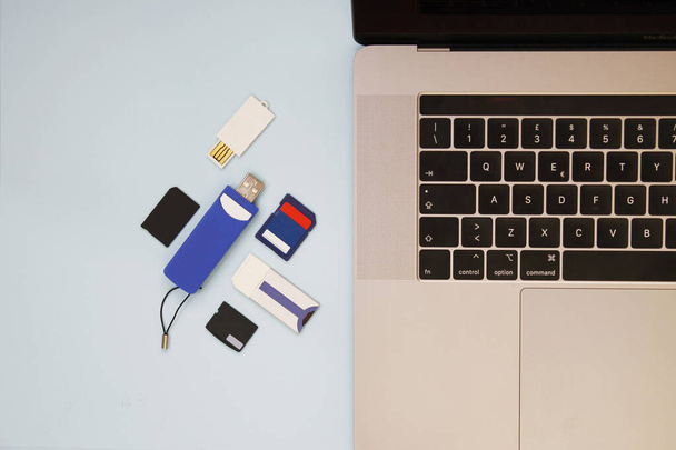 Laptop met geheugenopslagapparaten en lichtblauwe achtergrond - Foto, afbeelding