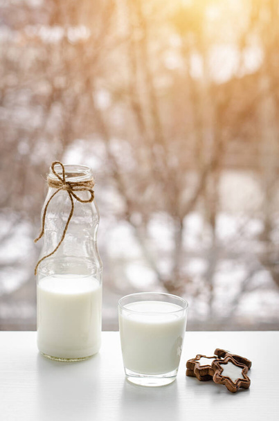 Полный стакан молока, шоколадное печенье и бутылка на столе для завтрака с видом на окно Wintwr
. - Фото, изображение