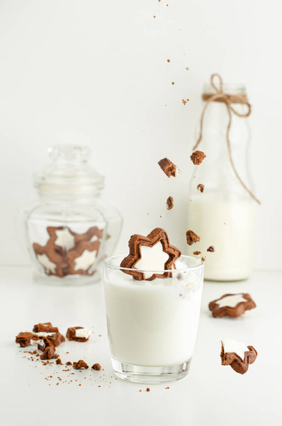 Un vaso de leche y galletas en forma de estrella sobre fondo blanco. Concepto de levitación
. - Foto, imagen