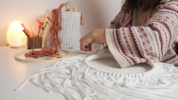 Boho style woman cutting circle wall hanging macrame with scissors on a white table with a yellow light - Footage, Video