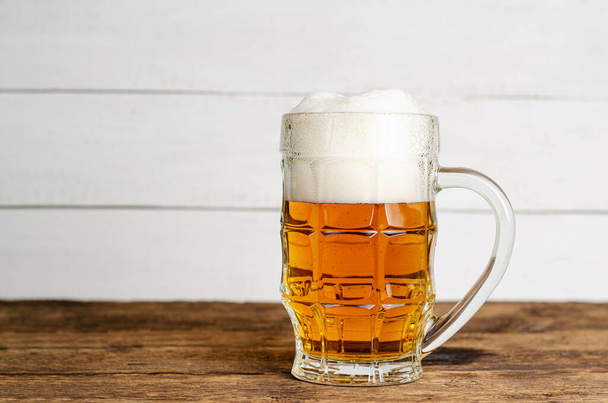 Full glass of blonde beer on white wooden backgroud. Copy space - Foto, afbeelding