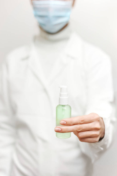 Close up view of female physician hands showing a personal antiseptic or sanitizer. Covid-19 protection measures. Doctor in white medical gown at clean white background. - Фото, изображение
