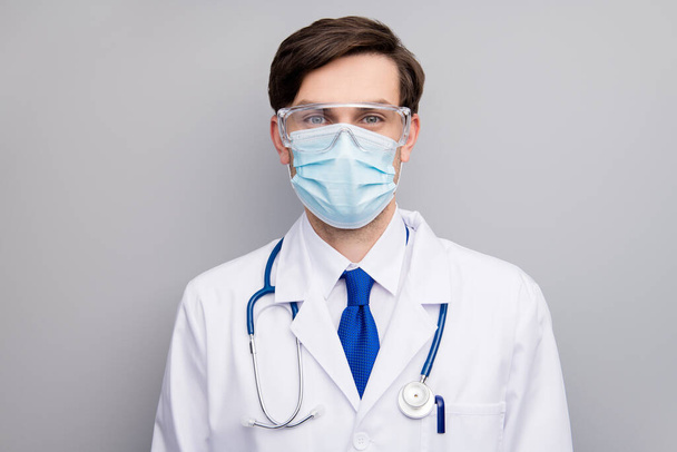 Φωτογραφία ελκυστικός όμορφος σοβαρός γιατρός τύπος επαγγελματίας χειρουργός ειδικός καλή διάθεση ακούσετε ασθενή φορούν μάσκα προστασίας του προσώπου ιατρική ομοιόμορφη εργαστηριακή ποδιά στηθοσκόπιο απομονωμένο γκρι φόντο - Φωτογραφία, εικόνα