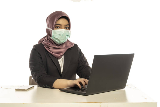 Business Lifestyle, Cute Malay Woman wearing hijab wearing facemask using laptop - Photo, Image