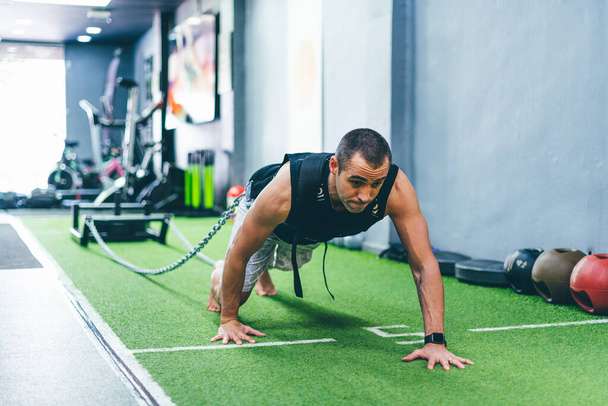 Latin boy faire de l'exercice physique dans la salle de gym traînant un traîneau avec du poids. Concept de formation
 - Photo, image