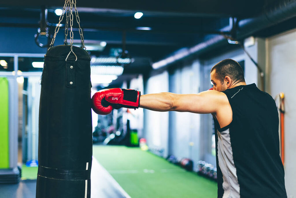 Latin boxer with red gloves hitting sack with the left. Training concept - Foto, Imagem