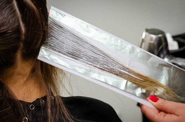 Διαδικασία εφαρμογής της σκόνης λεύκανσης στα μαλλιά των πελατών και περιτύλιγμα στο φύλλο. - Φωτογραφία, εικόνα