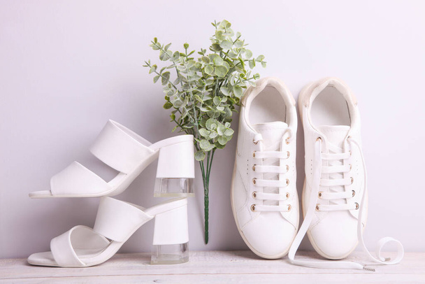 Κομψή γυναικεία σανδάλια και sneakers σε λευκό φόντο. - Φωτογραφία, εικόνα