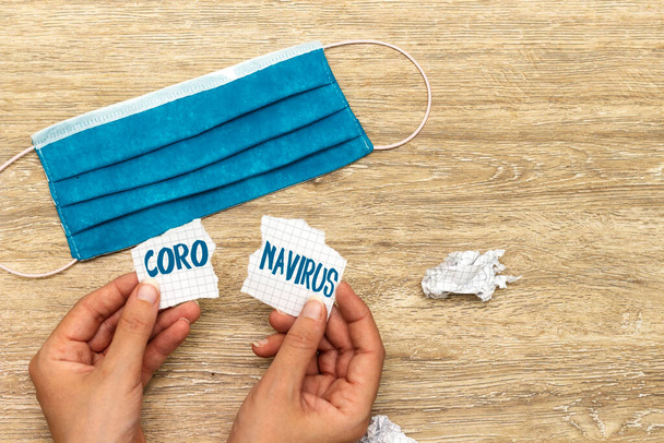 ręce trzymające papier łzawiący z koncepcją koronawirusa i niebieską maską - Zdjęcie, obraz