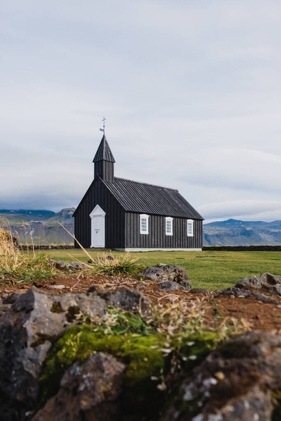 Black church in the meadow and field in Iceland. Icelandic scenic travel destination of religion. - Fotoğraf, Görsel