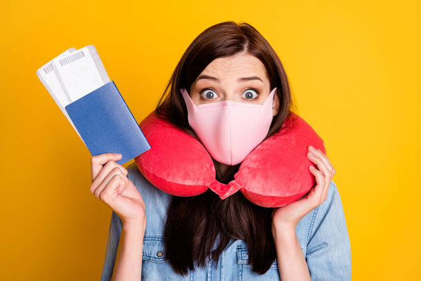 Portrait of shocked student girl hold tickets impressed border closed wear denim jeans shirt medical mask travel neck cushion isolated over bright shine color background - Photo, image