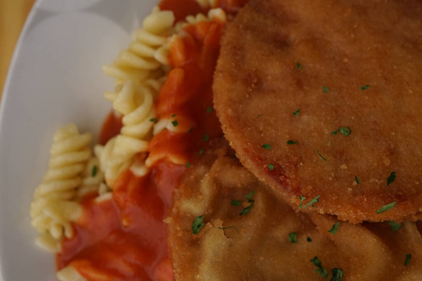 Original German Democratic Republic version of escalope chasseur with breaded Jagdwurst, noodles and tomato sauce                                - Photo, Image