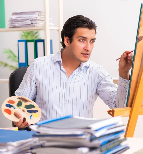 Νέος όμορφος υπάλληλος απολαμβάνει τη ζωγραφική στο γραφείο - Φωτογραφία, εικόνα