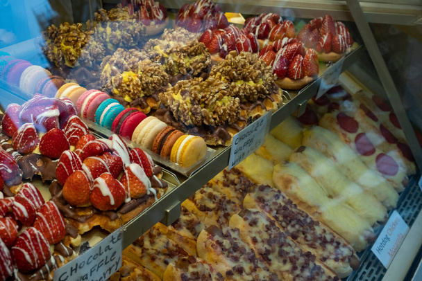 Heerlijke zoete taarten zijn in de winkel achter een glazen raam - Foto, afbeelding