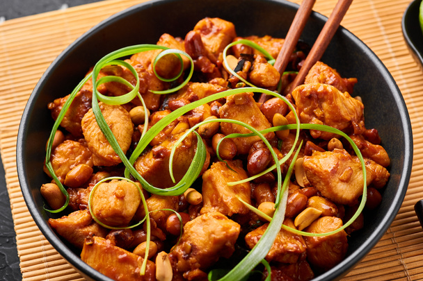 Kung Pao Chicken або Gong Bao Ji Ding на темному фоні. Sichuan Kung Pao - це китайська кухня з курячим м'ясом, перцем, арахісом, соусом і цибулею.. - Фото, зображення