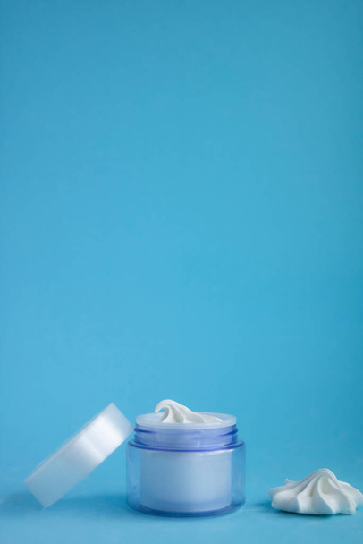 Hermoso frasco de crema azul con merengues sobre un fondo azul
 - Foto, imagen