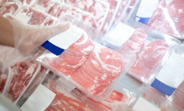 スーパーマーケットで選択した消費者のためのディスプレイトレイに新鮮な豚肉の肉スライスを準備するスーパーマーケットの従業員.  - 写真・画像
