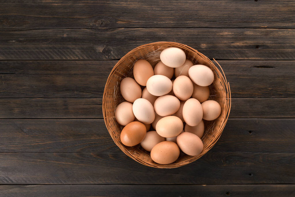 kuřecí vejce v košíku na dřevěném pozadí - Fotografie, Obrázek