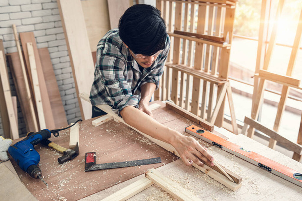 Carpenter Man pracuje na zpracování dřeva v truhlářství, DIY Craftsman je měření páskového nábytku dřeva v dílně. Mužský tesař DIY řemeslné práce je soustředěna jeho práce, Dělnické dovednosti Builder - Fotografie, Obrázek