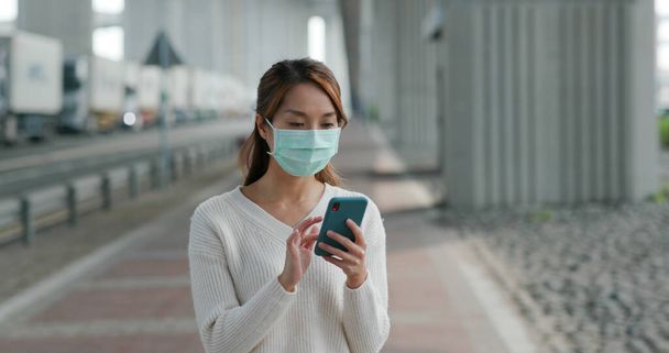 Donna indossare maschera medica e l'uso del telefono cellulare all'aperto - Foto, immagini