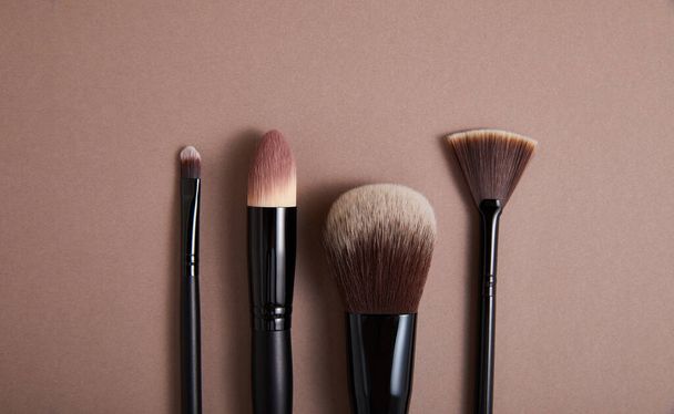 conjunto de pinceles profesionales de maquillaje facial sobre fondo beige, vista cercana, concepto de belleza
  - Foto, imagen