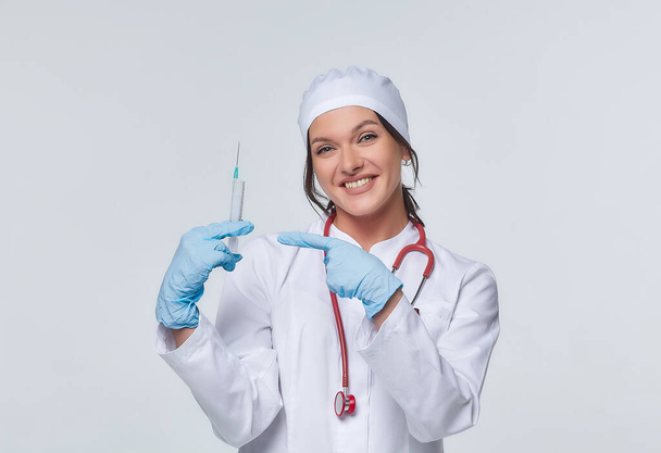 Medical concept of a female doctor in a white coat with a stethoscope, doctor. A female hospital worker looks at the camera and smiles, Studio, White background - Photo, Image