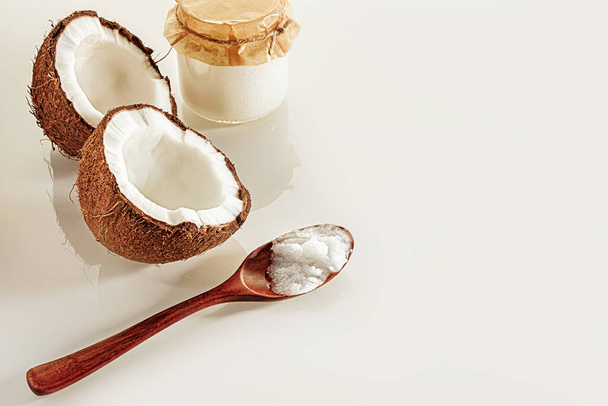 Komposition mit zwei Kokosnusshälften, einem Holzlöffel und Gläsern Kokosbutter. Das Konzept der gesunden Ernährung. - Foto, Bild